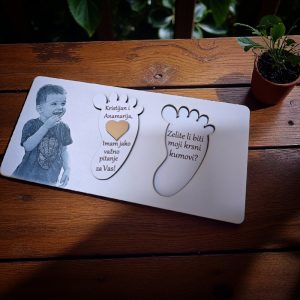 Drvena čestitka u obliku dječjeg stopala s fotografijom djeteta i natpisom “Hoćeš li biti moja kuma?”.