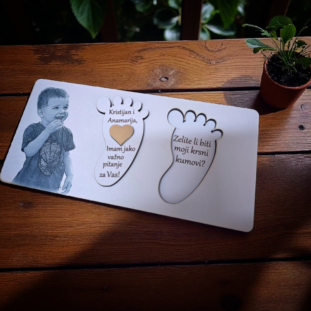 Drvena čestitka u obliku dječjeg stopala s fotografijom djeteta i natpisom “Hoćeš li biti moja kuma?”.