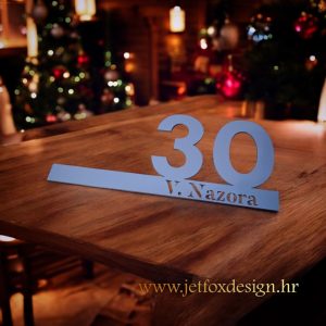 Akrilna pločica s kućnim brojem na liniji i personaliziranim tekstom poput “Obitelj Petrović” ili naziva ulice.