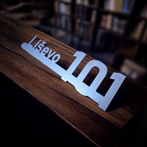 Akrilna pločica s kućnim brojem postavljenim iznad linije i ulice ispisane ispod, u modernom stilu.