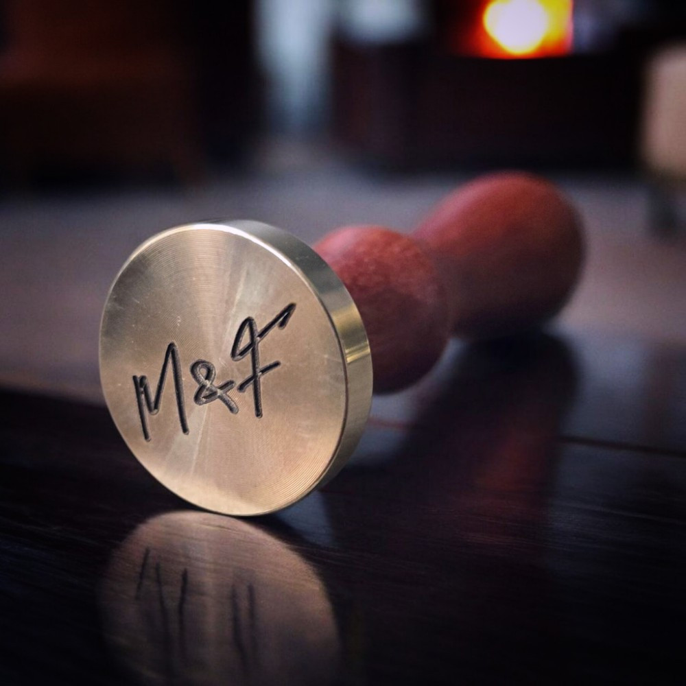 Personalizirani pečat za vosak s nježno ispisanim inicijalima u kurzivnom fontu, savršen za romantične detalje.