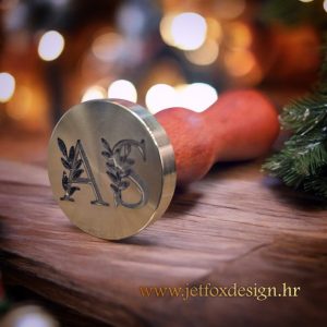 Pečat za vosak s inicijalima okruženim motivom maslinovih grana, elegantan detalj za pozivnice i posebne prigode.