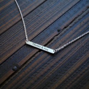 Ogrlica u srebrnoj boji s duguljastim kvadratnim privjeskom i personaliziranim imenima.