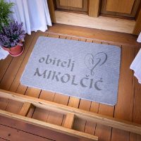 Ulazni otirač s natpisom "Obitelj", personaliziranim prezimenom i ugraviranim srcem – spoj funkcionalnog i emotivnog.